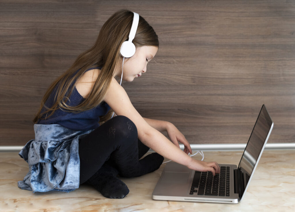 side view girl using laptop with headphones